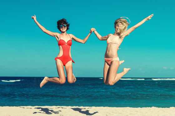 two woman in bikini jumping